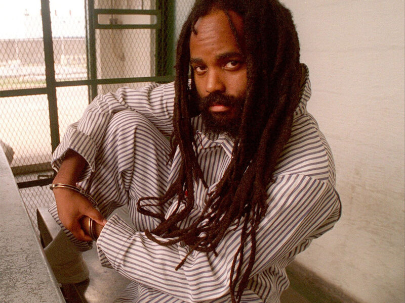 Mumia Abu-Jamal in pinstripes in cell.