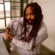 Mumia Abu-Jamal in pinstripes in cell.